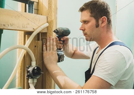 Handsome Male Worker Unmounting An Old Wooden Construction.