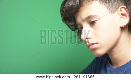 Profile Of A Teenager Boy, On A Green Background. Close-up. The Boy Is Concentrating On The Laptop S