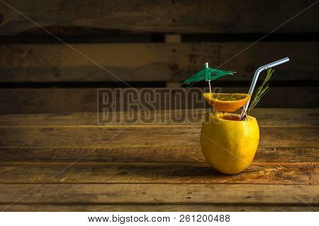 Cocktail Beach Boom Inside Lemon With Umbrella On Wooden Background With Studio Lights