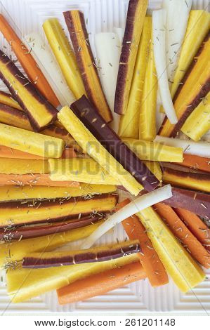 Colorful Yellow, Orange, Red And White Sliced Raw Carrots Plated And Sprinkled With Dry Rosemary Heb