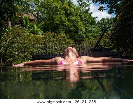 Relaxed woman in blue swimming pool. Girl in open swimming pool. Tropical jungle resort. Summer vacation banner. Ecotourism hotel swimming pool. Exotic holiday. Outdoor swimming pool with natural view