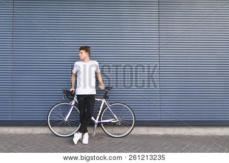 Young Student With A White Bike Stands Against The Wall And Looks To The Side. Sports Concept. Road 