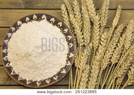 Harvest Of Wheat Spikelets And Flour On Wooden Background
