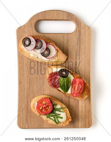 Open faced sandwich canape or crostini on a wooden serving board isolated on white background closeup. Top view.