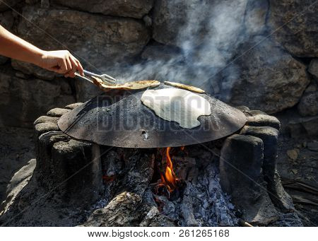 A Man's Hand Turning Over Lavash Baked On A Metal Plate