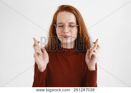 Beautiful Supertitious Young European Female In Spectacles Crossing Fingers, Praying Before Importan
