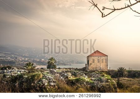 Amazing Landscape View Of Byblos, Traditional House, Rocks, Palms Trees, Mountains In The Background