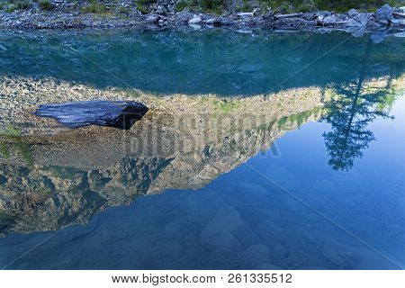 Reflection Of The Shore Of The Lake In The Watery Surface. Early Sunny Morning. The Large (lower) Sh