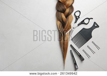 Flat Lay Composition With Braid, Hairdresser's Tools And Space For Text On Gray Background