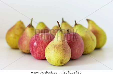 Ripe Yellow Pears And Red Apples Are In The Form Of A Pyramid On A Table On A White Background