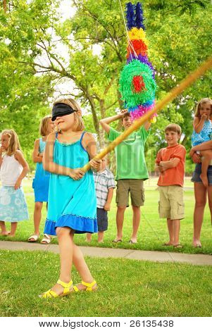 Giovane ragazza ad una festa all'aperto, colpendo una pinata