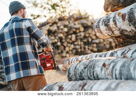 Professional Strong Lumberman Wearing Plaid Shirt Use Chainsaw On Sawmill. Strong Logger Worker Sawi