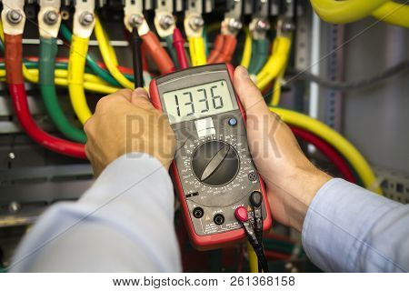 Electrical Tester In Hands Of Engineer Close-up. Electrician Technician At Work Inspecting Cabling C