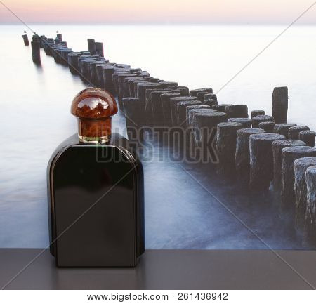 Eau De Toilette, Large Perfume Bottle In Front Of The Picture Of A Groyne In The Sea