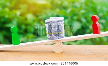 Wooden Figures Of People On Scales And Dollars Between Them. A Dispute Between Two Businessmen. Tria