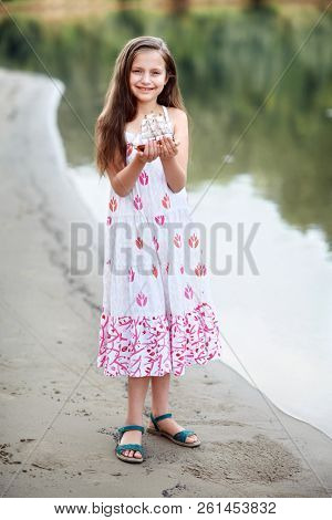 girl playing with a toy sailing ship by the river