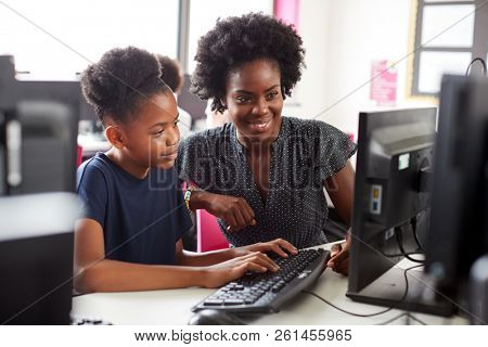 Teacher Helping Female High School Student Working at Screen In Computer Class
