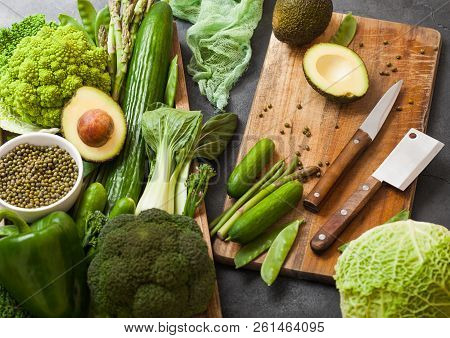 Assorted Green Toned Raw Organic Vegetables In Wooden Box On Dark Stone Background. Avocado, Cabbage
