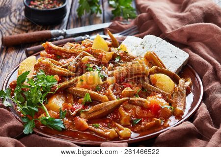 Stewed Okra With Tomato And Potato, Served With Feta Cheese Slices On A Earthenware Plate On A Rusti
