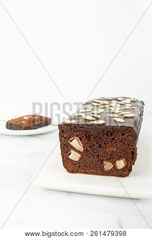 Closeup Of A Homemade Chocolate Loaf Cake With Pears On A White Marble Board And Marble Background W