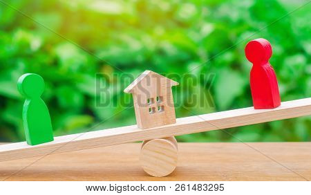 Wooden Figures On The Scales. Clarification Of Ownership Of The House, Real Estate. Rivals In Busine