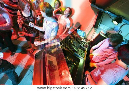 Gente ballare e flirtare vicino a cabina DJ in un locale notturno