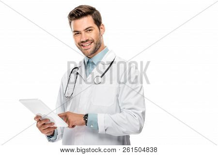 Smiling Young Male Doctor In Medical Coat Using Digital Tablet Isolated On White
