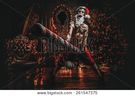 Bad Santa concept. Portrait of a nude tattooed Santa with purple dreads demonstrating antisocial behavior, rudeness and aggression. 