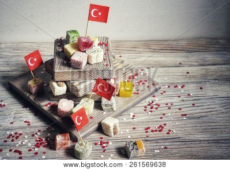 Various National Oriental Sweets, With Paper Flags Of Turkey, Turkish Delight On A Wooden White Brus