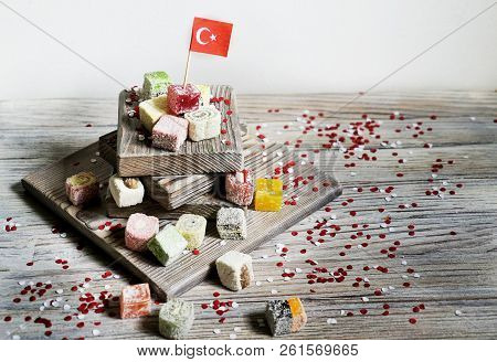 Various National Oriental Sweets, With Paper Flags Of Turkey, Turkish Delight On A Wooden White Brus