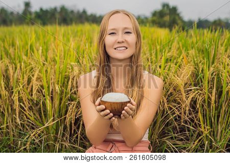 A Woman Is Holding A Cup Of Boiled Rice In A Wooden Cup On The Background Of A Ripe Rice Field