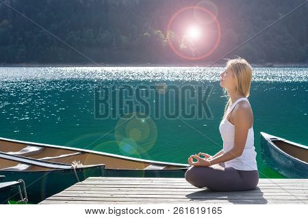 Beautiful Woman Is Doing Yoga Close To Lake. Young Girl Is Practicing Yoga And Meditating Outdoor. S