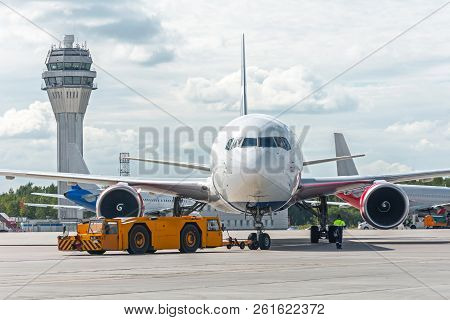 Airplane Execute Push Back Operation At Airport, On The Background Atc Tower.