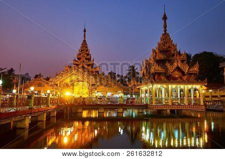 The Bright Illumination Of Kyay Thone Pagoda With Golden Pyatthat Roofs And Carved Decorative Detail
