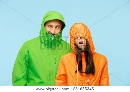The Young Couple Posing At Studio In Autumn Jacket Isolated On Blue. Human Negative Emotions. Concep