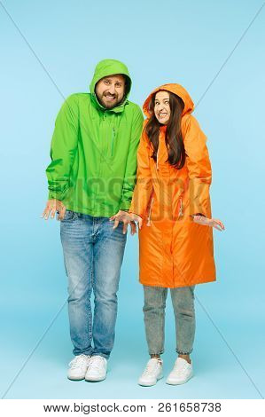 The Young Couple Posing At Studio In Autumn Jacket Isolated On Blue. Human Negative Emotions. Concep