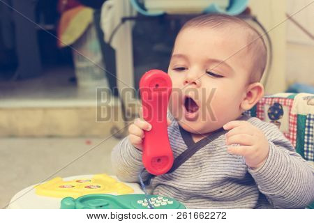 Baby Boy In The Walker Playing With Phone