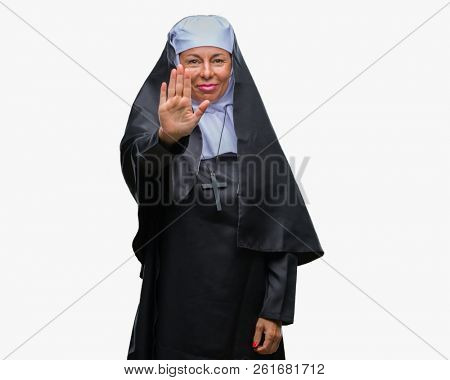 Middle age senior christian catholic nun woman over isolated background doing stop sing with palm of the hand. Warning expression with negative and serious gesture on the face.