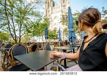Young Woman Enjoying Champagne Sitting At The Bar Outdoors Near The Cathedral In Reims City A Capita