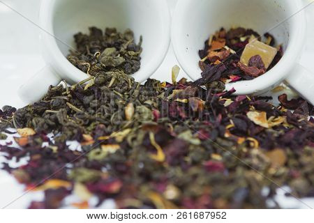 Green And Fruit Tea Leaves In White Ceramic Cups Background