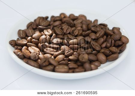 Top View Brown Coffee Beans And Seeds In Ceramic White Plate