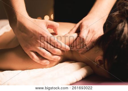 Men's Hands Make A Therapeutic Neck Massage For A Girl Lying On A Massage Couch In A Massage Spa Wit