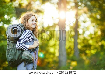 Female camper with backpack looking aroung while searching for camping place in the forest
