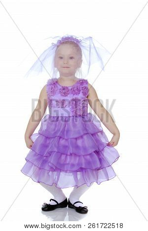 A Sweet Little Round-faced Girl In A Smart Purple Dress. With A Veil Covering His Face.she Makes A C