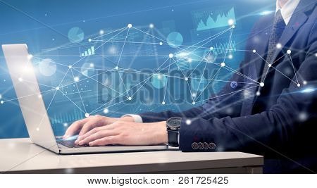 Businessman typing on laptop with linked reports charts grapghs around