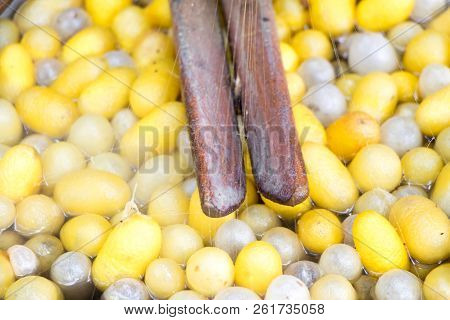 Closed Up Of Vintage Method For Silk Reeling And Yellow And White Cocoon On Hot Water Background