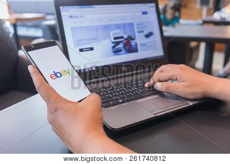 Chiang Mai, Thailand - Mar 18,2018: Man Holding Huawei With Ebay Apps On The Screen And Using Laptop