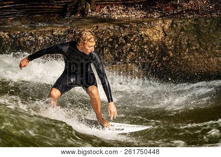 Munich, Germany - Sept 8, 2018: A Man Surfing In The Waves Of The Eisbach River In Downtown Of Munic