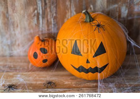 halloween and holidays concept - pumpkin and squash with scary faces, spiders and cobweb