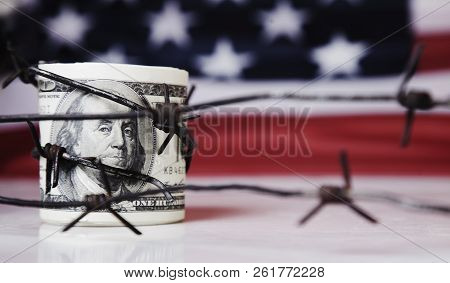 Us Dollar Money Wrapped In Barbed Wire On United States National Flag Background As Symbol Of Econom